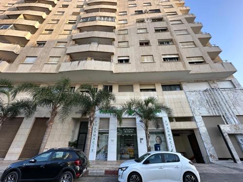 due auto parcheggiate di fronte a un palazzo alto di LovelyStay - Luxury & proximity to Corniche and TGV a Tangeri