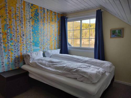 a bedroom with a bed with a window and curtains at Hus i Telemarkskanalens hjerte in Ulefoss