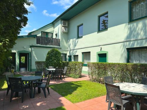 eine Terrasse mit Tischen und Stühlen vor einem Gebäude in der Unterkunft Írisz Panzió in Budapest