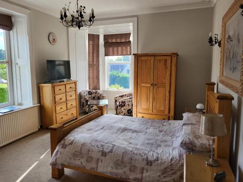 sypialnia z łóżkiem, telewizorem i oknami w obiekcie Macbeth Arms w mieście Lumphanan