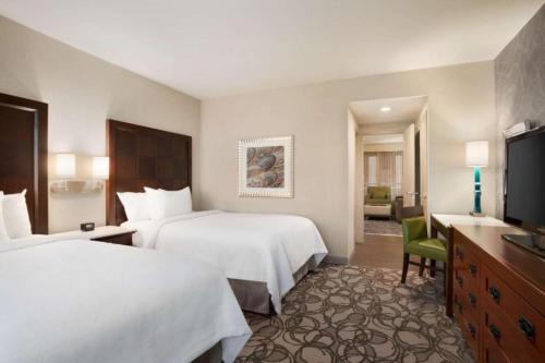 a hotel room with two beds and a television at Embassy Suites San Antonio Airport in San Antonio