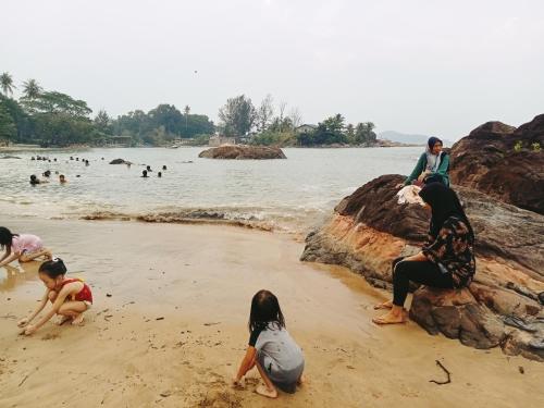 a group of people playing in the sand on the beach at The Dorm in Kampong Pandan