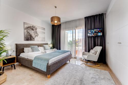 a bedroom with a bed and a chair and a window at Elegance Luxury Vacation House in Puerto de Santiago