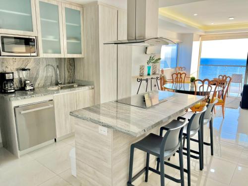 a kitchen with a counter and a table with chairs at Sunset View Malecón 1404 Vista panoramica al mar in Mazatlán