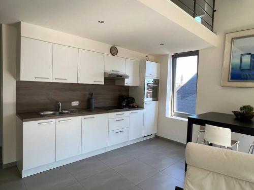 a kitchen with white cabinets and a table and a window at Alexa Residence - Appartement 2 in Roeselare