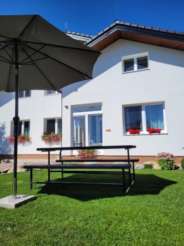 a picnic table with an umbrella in front of a house at Žiar Apartmány 43 in Žiar