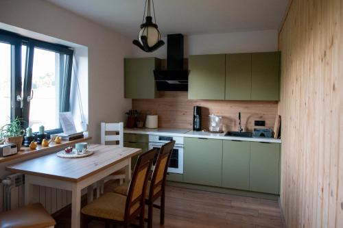 a kitchen with green cabinets and a table with chairs at Miętowe Zacisze Zator in Laskowa