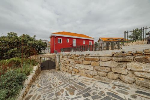 OPORTO GUEST Villa do Ribeirinho في بورتو: جدار حجري مع منزل احمر في الخلفية