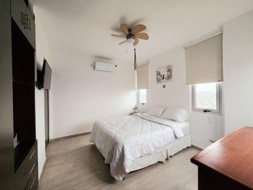 a white bedroom with a bed and a ceiling fan at Piso 19 - Acogedor apartamento de 3 Recámaras in Panama City