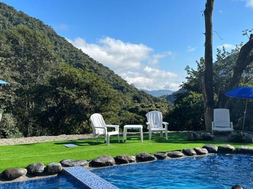 two chairs and an umbrella next to a swimming pool at Tambo Quinde in Tandayapa
