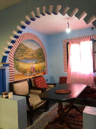 a living room with a table and a painting on the wall at Farm Stay Mharchen in Chefchaouene