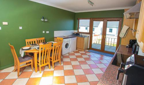 a kitchen with a table and chairs and a washing machine at The Heather Dew in Portstewart