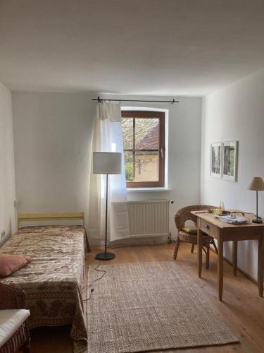 una camera da letto con un letto, un tavolo e una finestra di Uhlenmühle a Aub