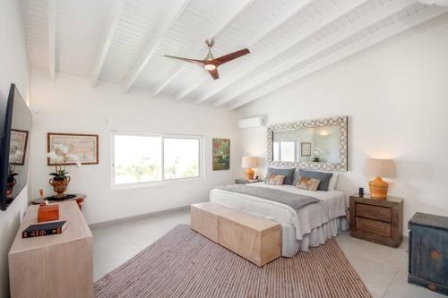 a white bedroom with a bed and a ceiling fan at Puerta Al-Mar Villa in Simpson Bay