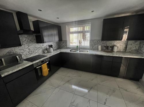a kitchen with black cabinets and marble counter tops at Modern 4 Bed - 10 mins to centre in Liverpool