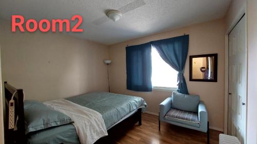 a bedroom with a bed and a chair and a window at Green Village in Calgary