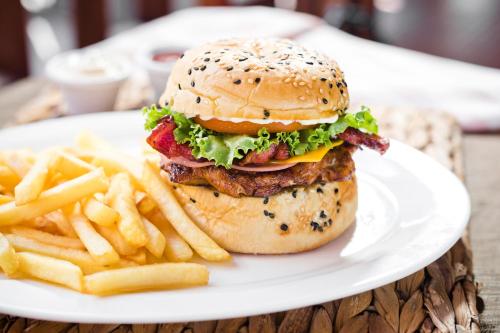 a hamburger and french fries on a white plate at Hotel Boyeros in Liberia
