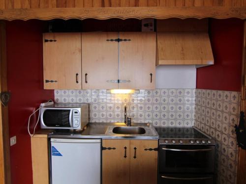 une petite cuisine avec un évier et un micro-ondes dans l'établissement Studio cosy pour 4 à L'Alpe d'Huez, balcon sud, proche pistes et commerces, animaux bienvenus - FR-1-405-197, à Huez