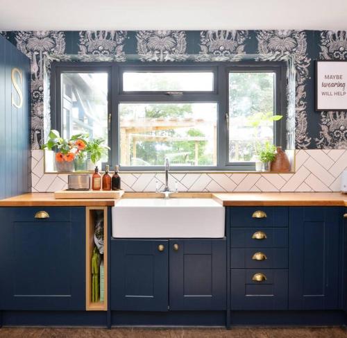 a blue kitchen with a sink and a window at Stunning, high end country house in Nether Whitacre