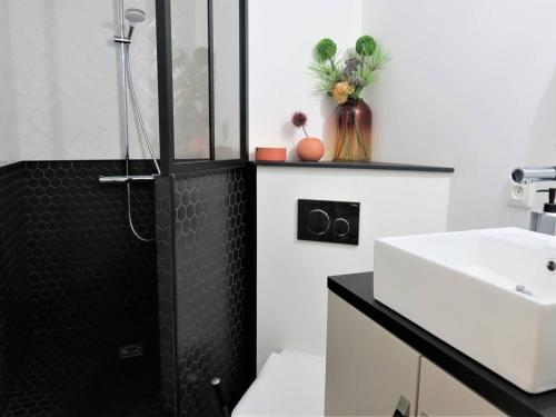 La salle de bains est pourvue d'une douche noire et d'un lavabo. dans l'établissement Appartement rénové avec balcon, parking et accès direct à la plage de Trestraou - Perros-Guirec - FR-1-368-260, à Perros-Guirec