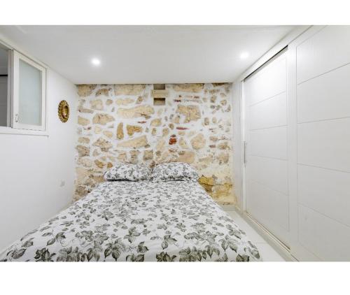 uma cama num quarto com uma parede de pedra em Catedral em Cartagena das Índias