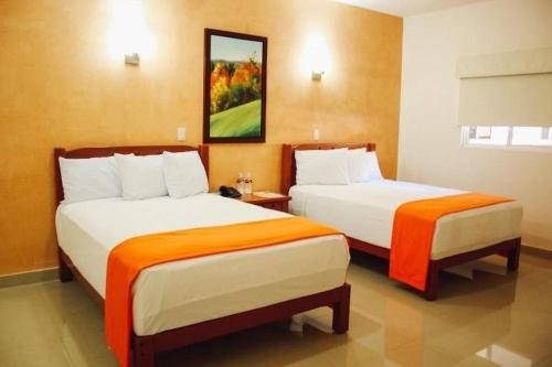 a hotel room with two beds with orange sheets at Gran Hotel Residencial Galerias in Ciudad Obregón