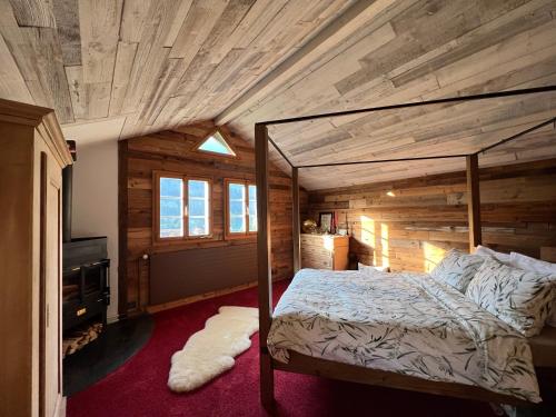 Romantic private superior Swiss Chalet with Hottub في لونغرن: غرفة نوم بسرير وسقف خشبي