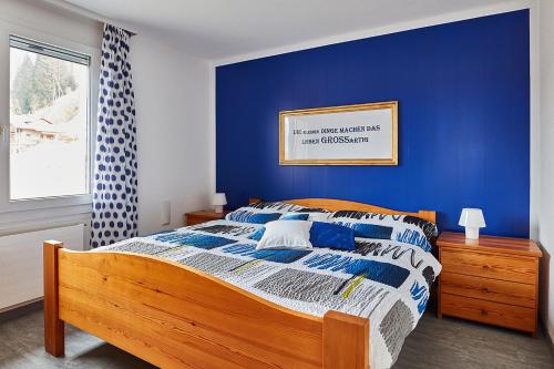 Schlafzimmer mit einem Bett mit blauer Wand in der Unterkunft Elfe-Apartments FerienMietWohnungen in Emmetten