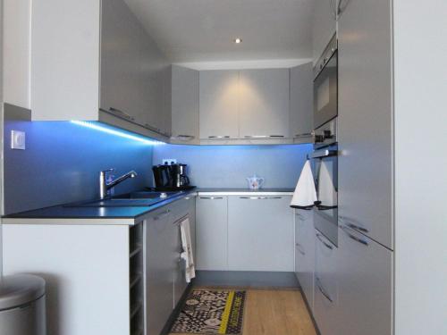 une cuisine avec des armoires blanches et un mur bleu dans l'établissement Appartement cosy avec balcon, 6 pers, proche pistes et commerces, Huez - FR-1-405-199, à Huez