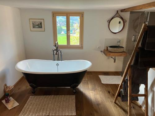 a bath tub in a bathroom with a window at Romantic private superior Swiss Chalet with Hottub in Lungern