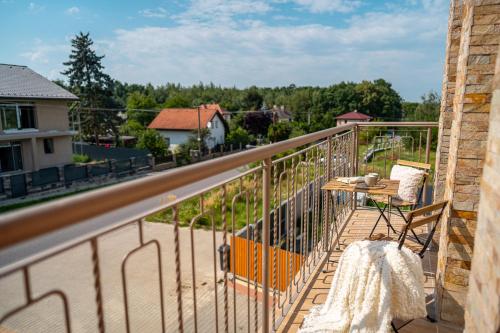 a balcony with a table and chairs and a road at LASKARA Garden Apartment by Prague Forest in Nové Jirny