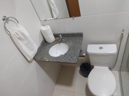 La salle de bains est pourvue de toilettes blanches et d'un lavabo. dans l'établissement Maper Park Carajás, à Parauapebas