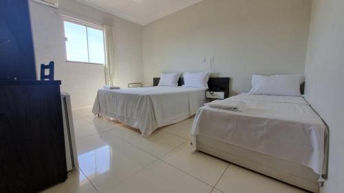 biały pokój z 2 łóżkami i oknem w obiekcie Maper Park Carajás w mieście Parauapebas