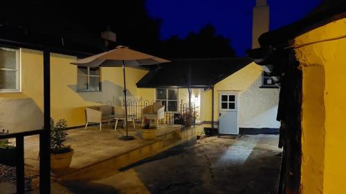 a house with a patio with an umbrella at night at Wellington Farm Devon near sidmouth beach & AONB- dog friendly in Honiton