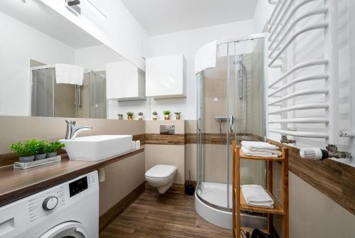 a bathroom with a sink toilet and a washing machine at Apartament Kasprzaka Bliska Wola in Warsaw