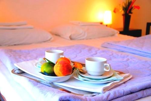 ミラノ・マリッティマにあるHoliday Home Michelaのベッドの上に朝食トレイ(カップ2杯、フルーツ付)