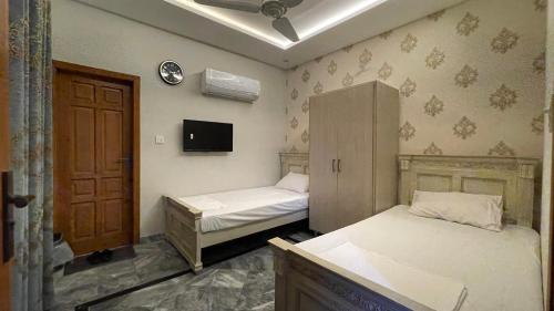 a room with two beds and a cabinet and a tv at Midways Guest House and Hotels in Islamabad
