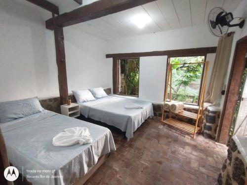 1 dormitorio con 2 camas y ventana en Recanto Flor de Jasmim, en Ilhabela