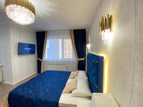 Un dormitorio con una cama azul y una ventana en ЖК Лето новая однокомнатная квартира, en Astana