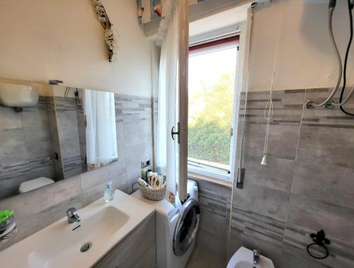 a bathroom with a sink and a washing machine at Alghero Sa Stella Casa Vacanze in Fertilia