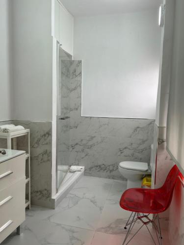 baño con aseo y silla roja en Coliseo Premium Apartment, en Sevilla