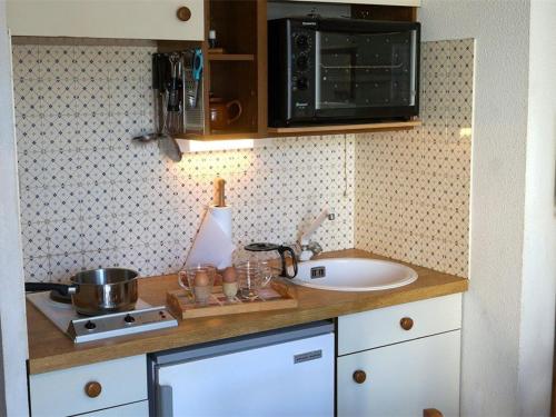 eine Küchentheke mit einer Spüle und einer Mikrowelle in der Unterkunft Appartement Bagnères-de-Luchon, 2 pièces, 4 personnes - FR-1-313-152 in Luchon