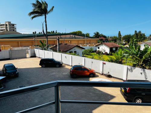 a parking lot with cars parked in front of a fence at Lomes cozy home in Dar es Salaam