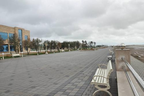 a row of benches on a sidewalk near the beach at Гостевая Квартира in Sumqayyt