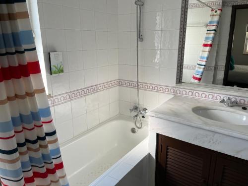 uma casa de banho com uma banheira, um lavatório e um espelho. em House´s Golf em Almancil