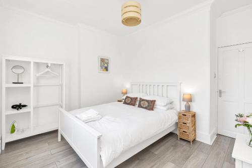 um quarto branco com uma cama branca e prateleiras brancas em Modern Two Bedroom Apartment with Free Parking! em Londres