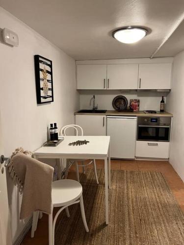 a small kitchen with a white table and chairs at Källarlägenhet Örgryte in Gothenburg