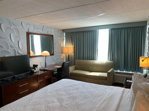 a hotel room with a bed and a chair and a television at Albany Airport Inn in Albany