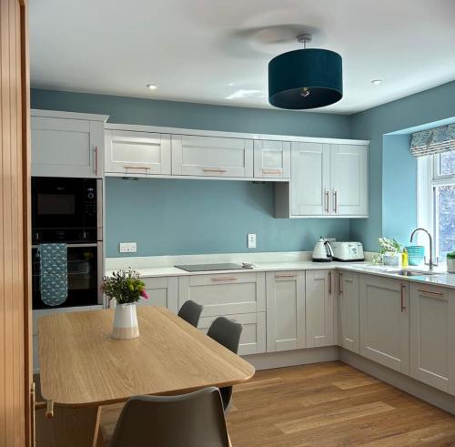 a kitchen with white cabinets and a wooden table at The Fiddich Luxury Home in Craigellachie in Craigellachie