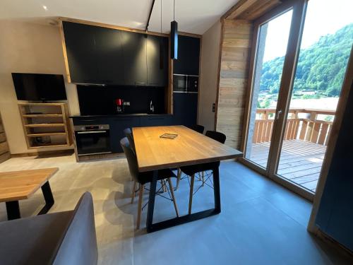 a kitchen with a wooden table and a large window at Gite Roche Des Ducs avec Piscine toute l'année, Spa, Sauna, Hammam in Rochesson